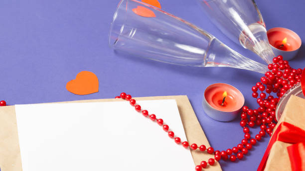 istock Valentine's day. two glasses, envelope with sheet blank, hearts, candles on Very Peri, Trendy violet color background. Romantic dinner couple concept 1363947992