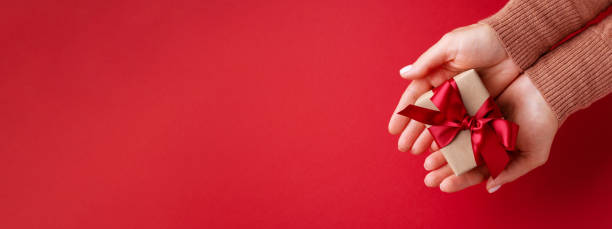 istock Female's hands holding gift box with red bow. 1363950900