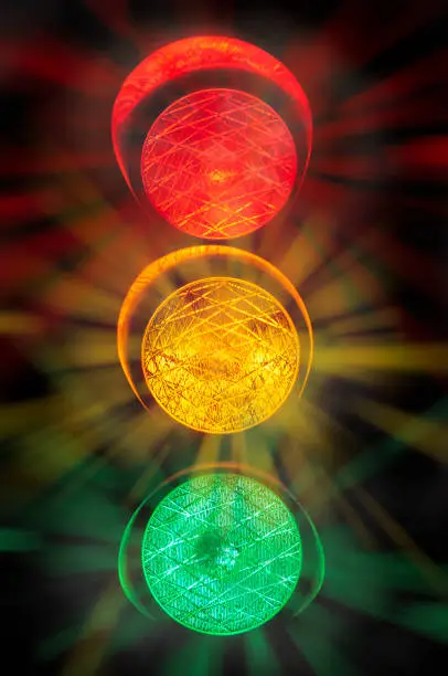 All three lights of a traffic light when shining with a black background and haze