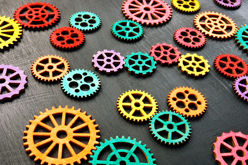 Multi-colored gear wheels on a dark surface. Variety and interaction.
