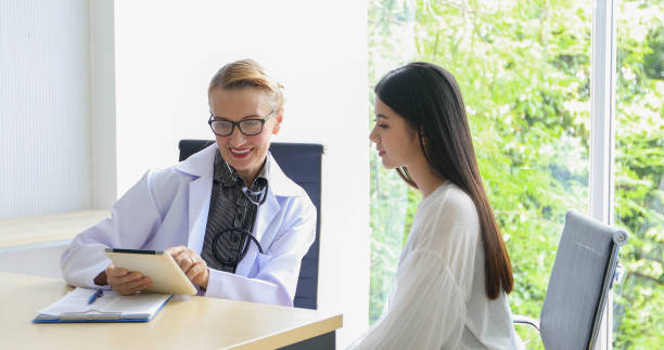 Women Doctor talk with woman patient in his office at Hospitals,Healthcare concept stock photo