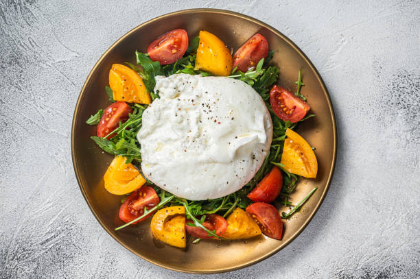 istock Italian Burrata cheese with cherry tomatoes and fresh arugula. White background. Top view 1363953331