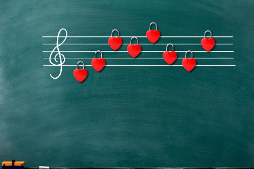 Musical score of the red heart shape padlock on the chalkboard with copy space.