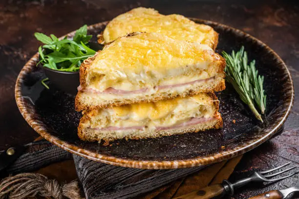Croque Monsieur toasted sandwich with Cheese, Ham, Gruyere and Bechamel Sauce. Dark background. Top view.