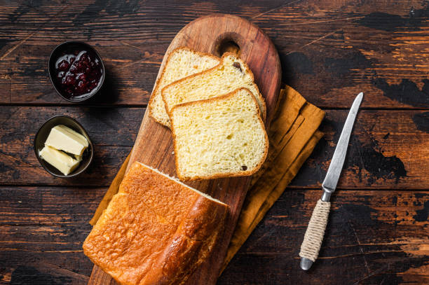 istock Brioche bread on breakfast table with butter and jam. Wooden background. Top view 1363956612