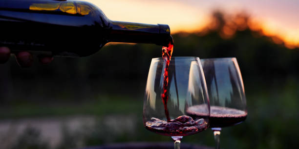 Pouring redwine into glasses in the vineyard Pouring red wine into glasses in the vineyard at sunset red wine stock pictures, royalty-free photos & images
