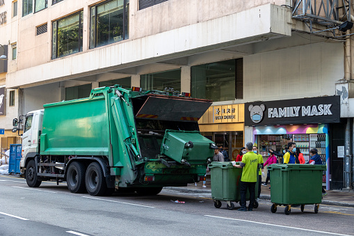 Scene Of Building Exterior, People Walking On The Street And Refuse Collectors Loading Garbage Into Garbage Truck In Mexico City Mexico