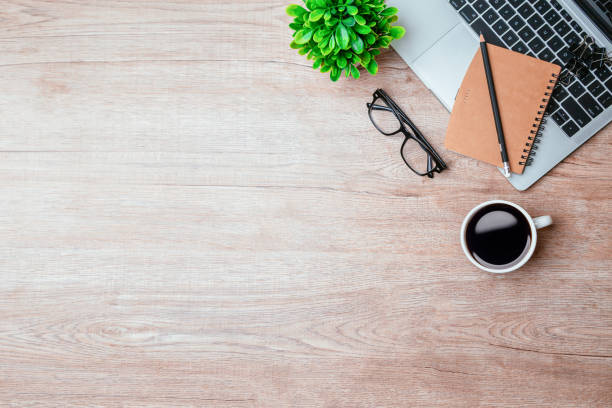 istock Work from home. desk office with laptop, blank notepad, coffee cup and pen on wood table. Flat lay top view copy spce. 1363964607
