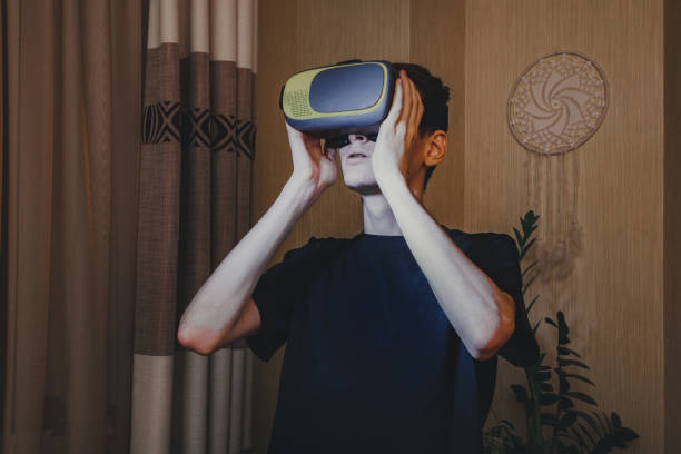 istock Young man in a VR helmet watching in virtual reality in the home interior 1363966135