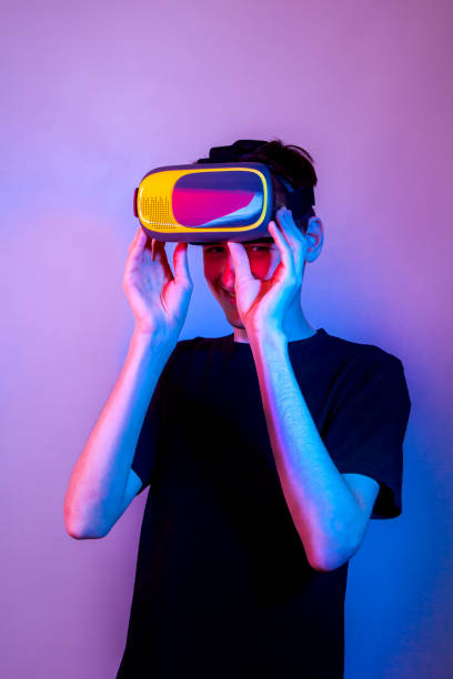 istock A young man looks out from under a virtual reality helmet and laughs 1363966364
