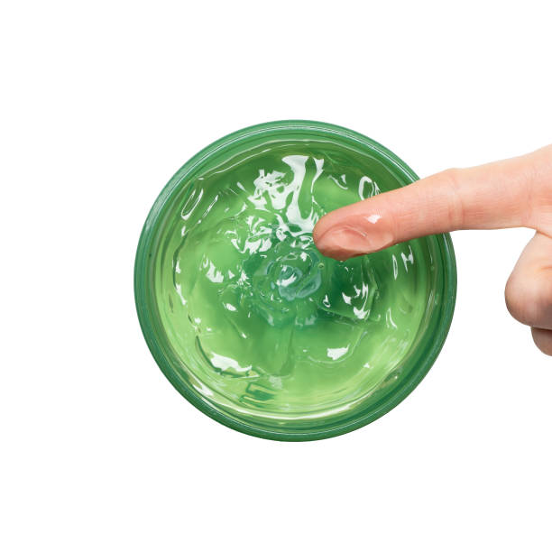 Aloe Vera Gel on a female hand which is scooping it from a jar on white background, top of view. Aloe Vera is natural remedy for sunburn relief. Natural alternative medicine. stock photo