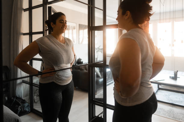 proudly looking at her own reflection - mirror women looking reflection imagens e fotografias de stock