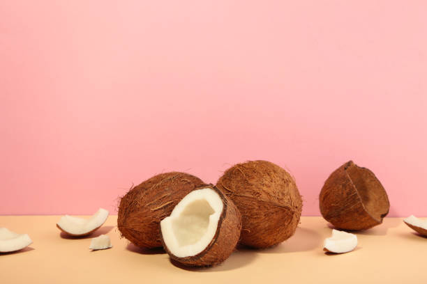 istock Coconut on a pink background. Halves and whole coconuts. Top view. 1363973306