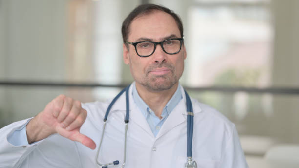 istock Middle Aged Doctor Showing Thumbs Down Sign 1363974638