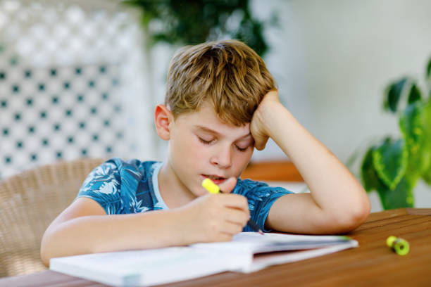 istock Hard-working happy school kid boy making homework during quarantine time from corona pandemic disease. Healthy child writing with pen, staying at home. Homeschooling concept 1363976804