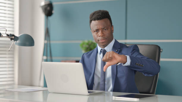 istock African Businessman Showing Thumbs Down Sign While using Laptop at Work 1363979395