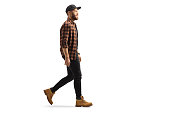 Full length profile shot of a young trendy man in a shirt and cap walking