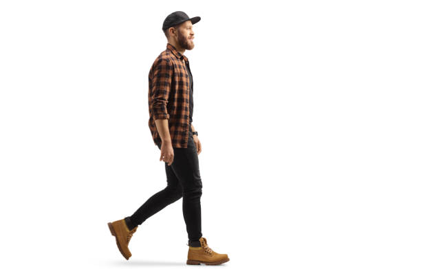 Full length profile shot of a young trendy man in a shirt and cap walking Full length profile shot of a young trendy man in a shirt and cap walking isolated on white background model object stock pictures, royalty-free photos & images
