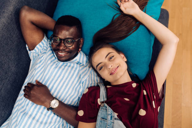 istock Multiracial couple lying down on the sofa and enjoying together 1363980962