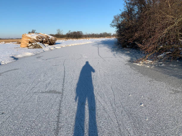 l'ombra di un pattinatore su ghiaccio in un paesaggio invernale nel weerribben wieden durante una bella giornata invernale - wieden weerribben foto e immagini stock