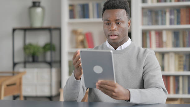 istock African Man making Video Call on Tablet in Library 1363982140