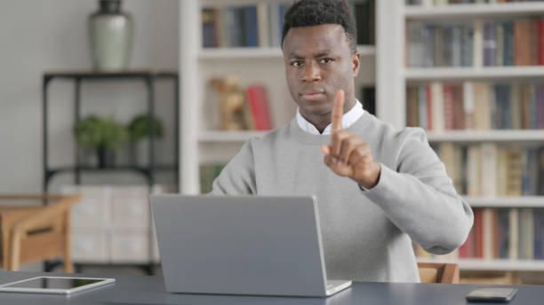 istock African Man Shaking Head as No Sign while using Laptop in Library 1363982229