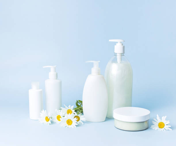 istock Cosmetic bottle containers with chamomile flowers on a blue minimalistic background flat lay. Blank label for branding mock-up. Natural beauty product concept. 1363982797