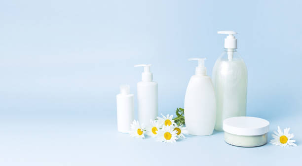 istock Cosmetic bottle containers with chamomile flowers on a blue minimalistic background flat lay. Blank label for branding mock-up. Natural beauty product concept. 1363982814