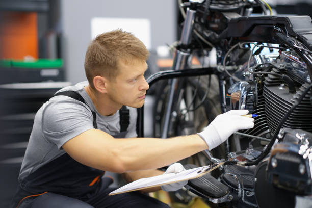 ガレージの男がバイクをチェックしている - 修理工 ストックフォトと画像