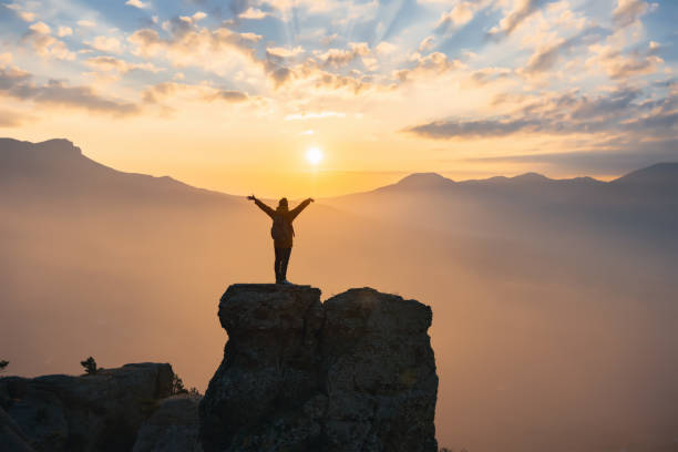 istock Silhouette hiker in mountains with raised arms at sunset 1363987243