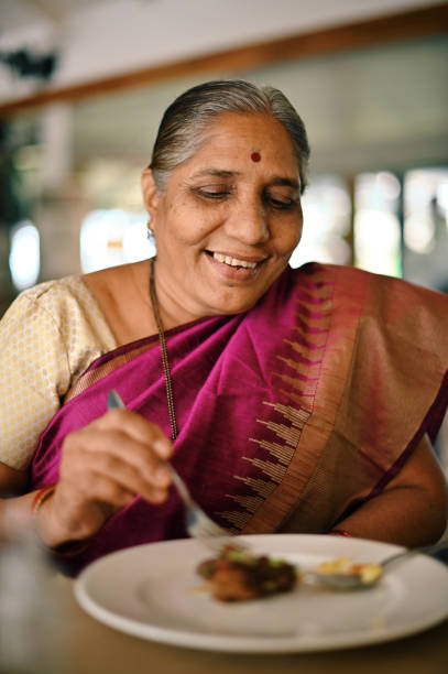 Senior woman eating chicken wings appetizer in a restaurant
