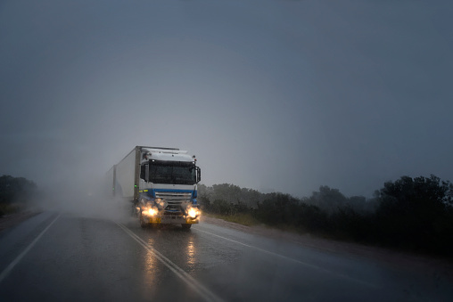 Bad weather on the highway. Long trucks - road trains are driving in a dangerous situation with water on the windshield