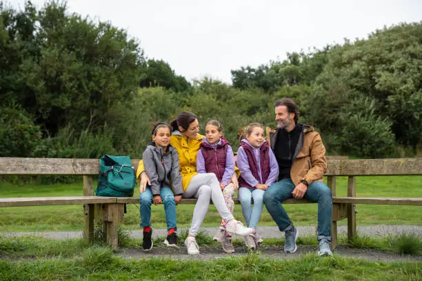 Front-view of Caucasian parents with their young triplets sitting together in the North East of England. They are wearing warm clothing, with their arms around each other.
