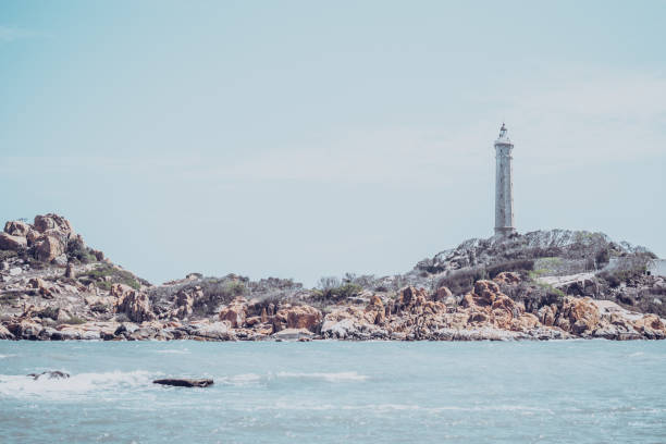 morze przyroda panoramiczny widok krajobraz tło. ocean skaliste klify zalesiona wyspa. czyste błękitne niebo. latarnia morska na szczycie góry. sygnał ostrzega żeglarzy wrak statku, koncepcja podróży nadzieja cel życia - sea storm sailing ship night zdjęcia i obrazy z banku zdjęć