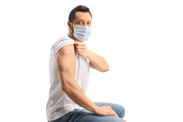 istock Young man with a mask showing his arm with a vaccine patch 1363988883