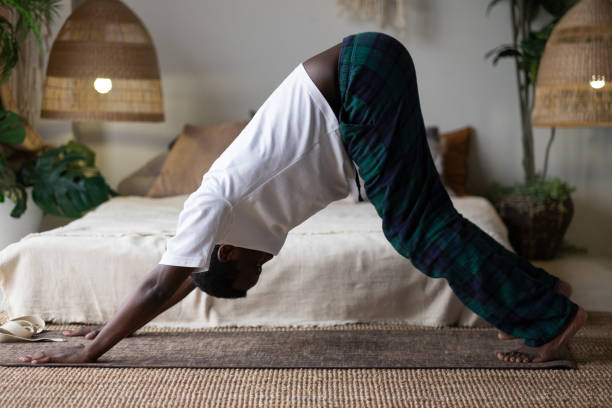 Young african man working out, standing in yoga downward facing dog pose, adho mukha svanasana Young african man working out, standing in yoga downward facing dog pose, adho mukha svanasana, asana from Surya Namaskar sequence, Sun Salutation complex downward facing dog position stock pictures, royalty-free photos & images