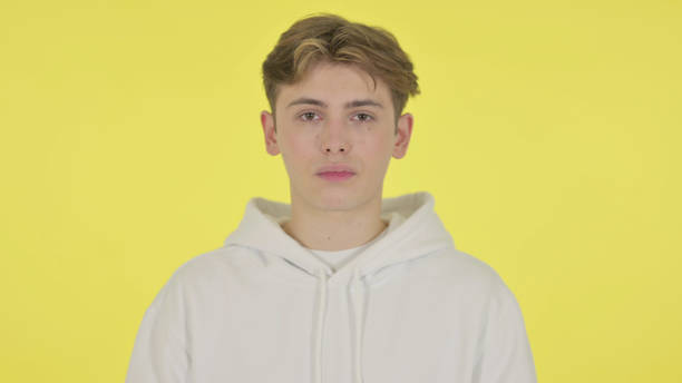 istock Serious Young Man Looking at the Camera on Yellow Background 1363991468
