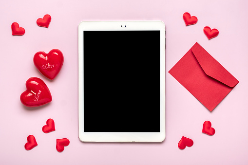 digital tablet for chooses gifts, makes purchase, envelope, red hearts on pink table Top view Flat lay Holiday shopping list, Happy Valentine's day, party, online shop concept Mock up.