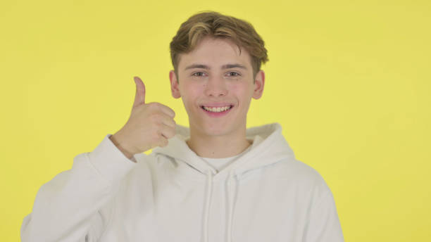 istock Young Man showing Thumbs Up Sign on Yellow Background 1363993364