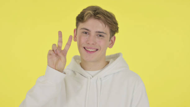 istock Young Man Showing Victory Sign on Yellow Background 1363993382