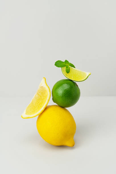 istock Fresh bright yellow lemon, green juicy lime slice, mint leaf balanced on grey background. Ripe citrus fruits on top of each other. Healthy diet superfood. Ingredients for lemonade. Minimal still life 1363995932