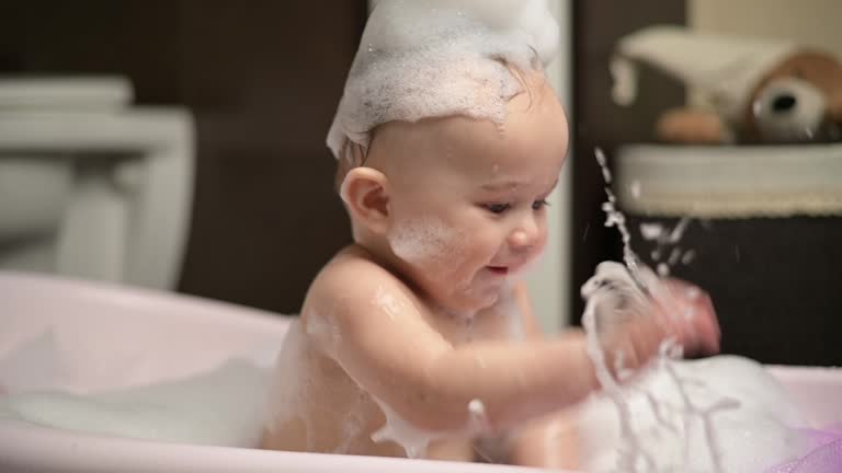 A little boy splashes in a bubble bath. Slow motion