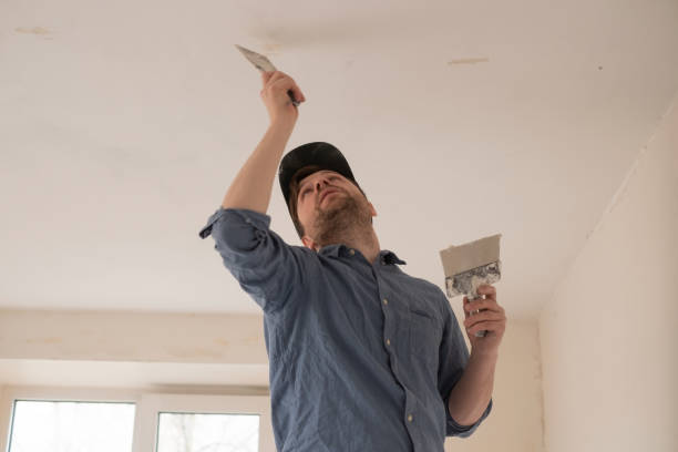 istock Man with putty knife repairing ceiling at flat. 1363997166