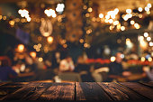 テーブルレストラン。夜のレストランホールのぼやけたインテリアに木製のキッチンやバーテーブル、ライトと訪問者が付いています。
