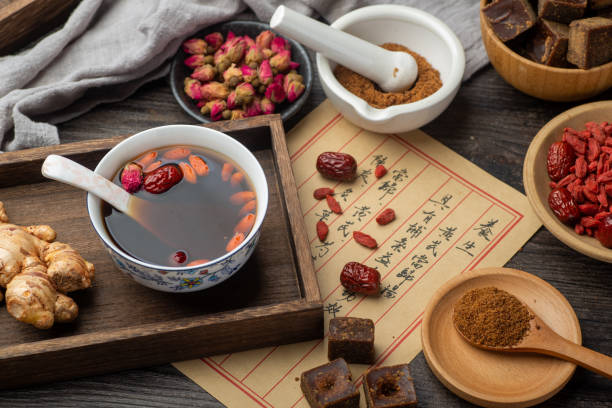 té de azufaifo de jengibre con azúcar moreno y libros de medicina clásica china sobre la mesa - soup chinese culture herbal medicine chinese medicine fotografías e imágenes de stock