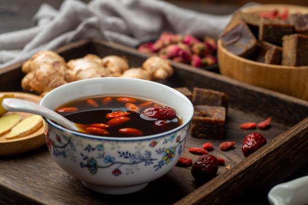 chá de jujuba de gengibre de açúcar mascavo e livros médicos clássicos chineses sobre a mesa - soup chinese culture herbal medicine chinese medicine - fotografias e filmes do acervo