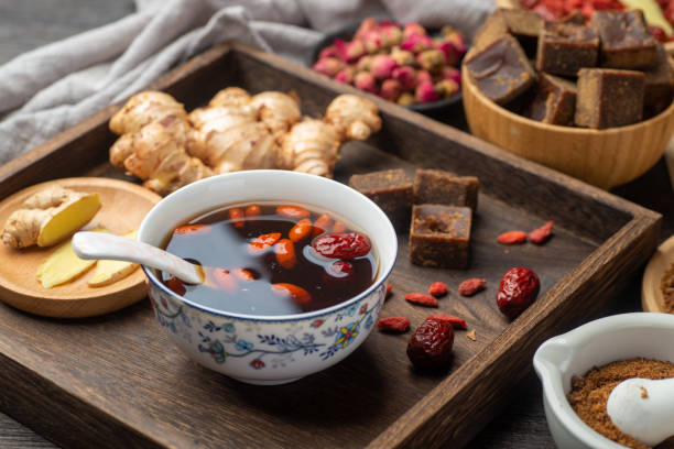 chá de jujuba de gengibre de açúcar mascavo e livros médicos clássicos chineses sobre a mesa - traditional chinese medicine - fotografias e filmes do acervo