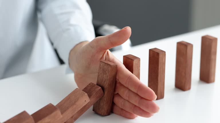 Risk and strategy in business is hand stopping the fall of wooden block