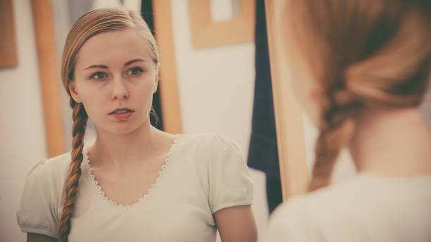 istock Woman looking at her reflection in mirror 1364003049