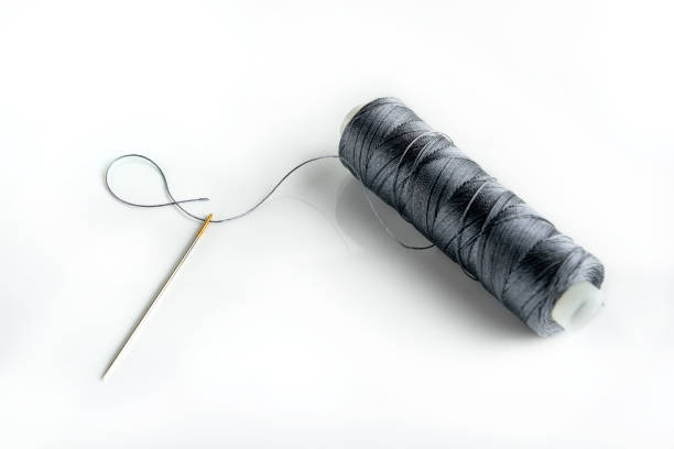 istock needle and spool of thread close-up on a white background with copy space. Thread through the eye of the needle. 1364004660